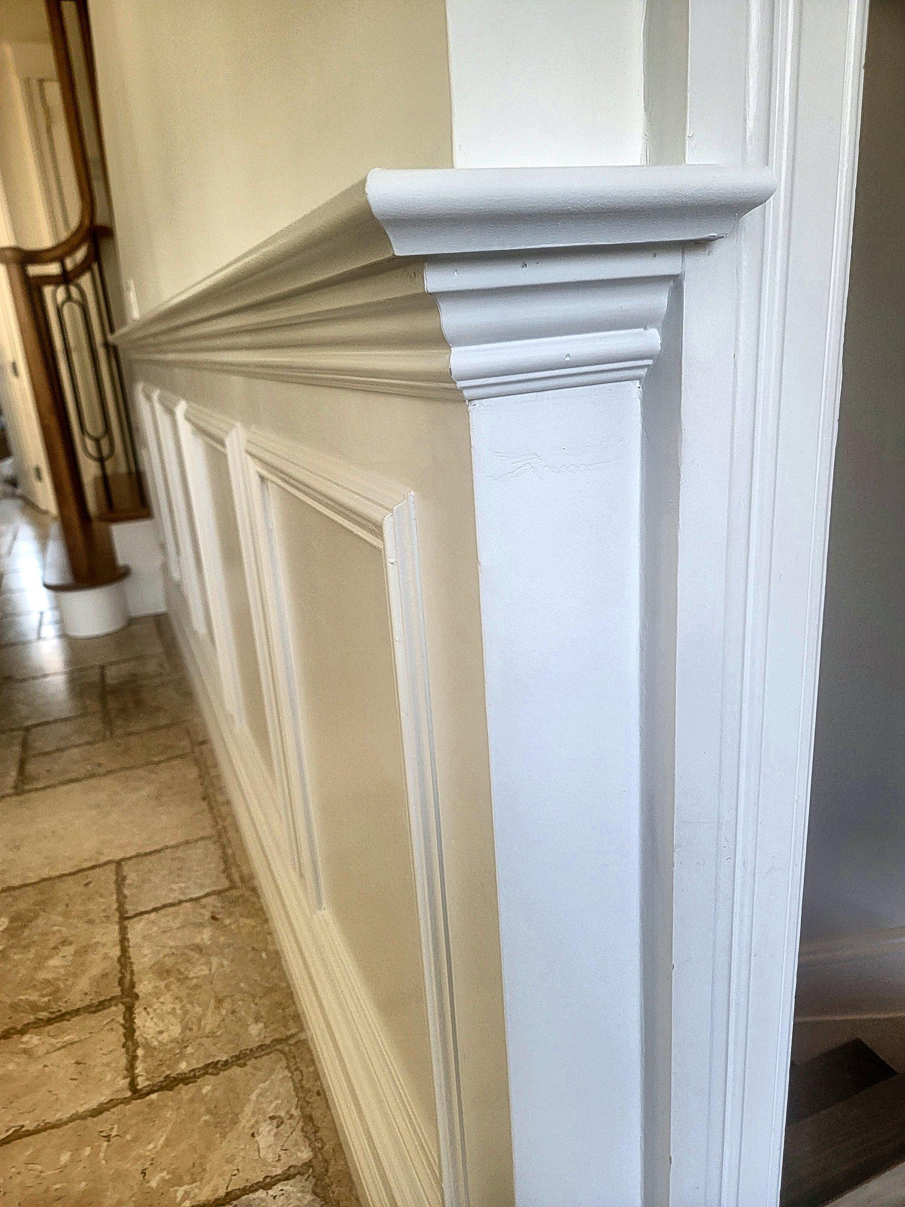 A fluted column meeting crown molding and raised-panel wainscot.