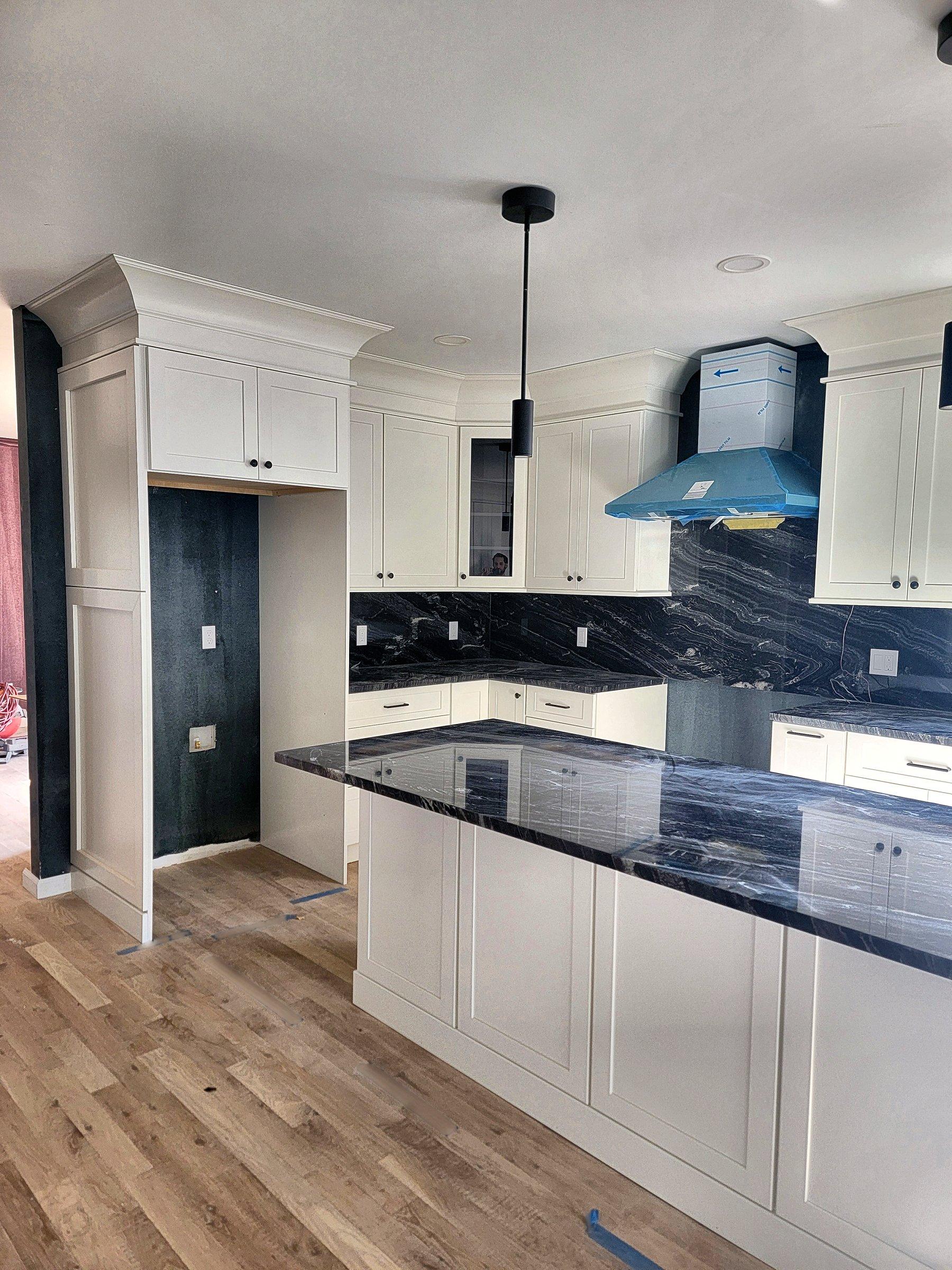 A white shaker kitchen with a dark island and a granite top.